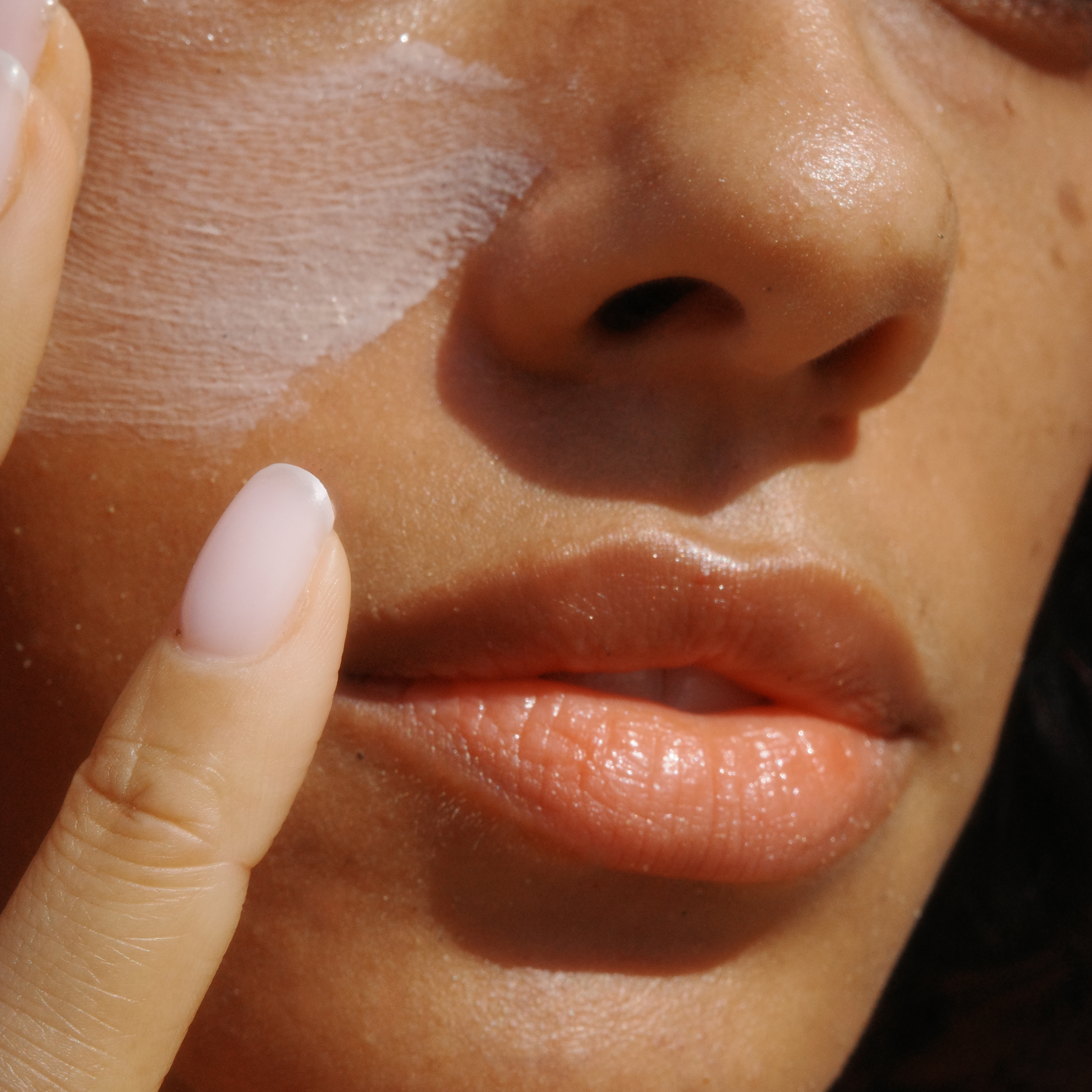 Close-up of a person applying sunscreen to their face.