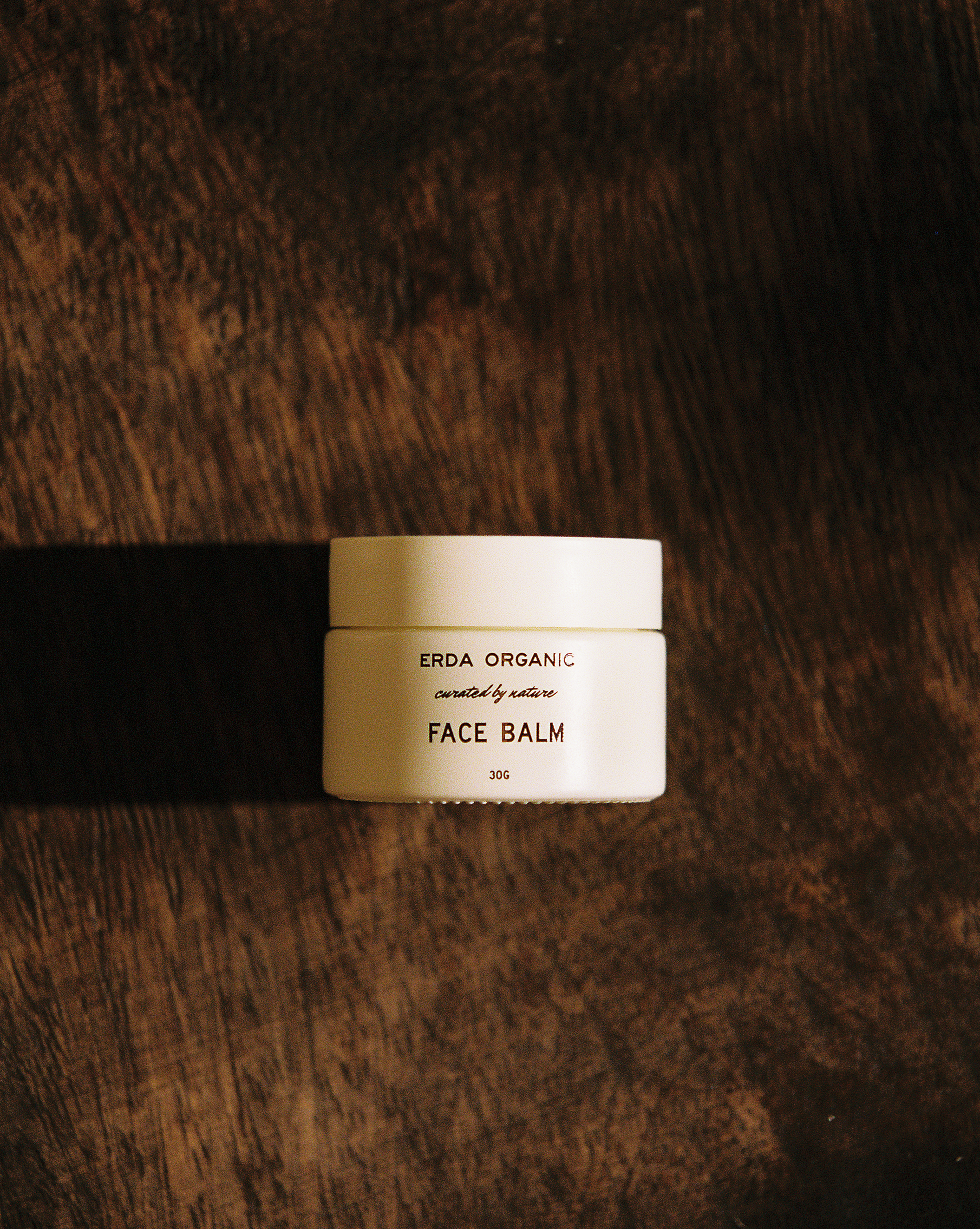 Jar of Erda Organic Face Balm on a brown textured surface